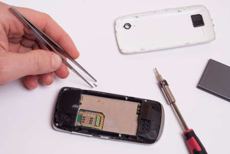 technician with a tool in his hand repairing a mobile phoneの写真素材