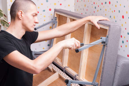 worker at home repairing a folding sofaの写真素材