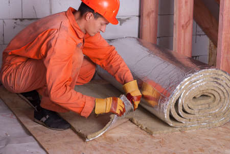 worker cuts off a strip of mineral woolの写真素材