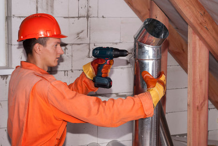 worker in the attic connects metal air ductsの写真素材