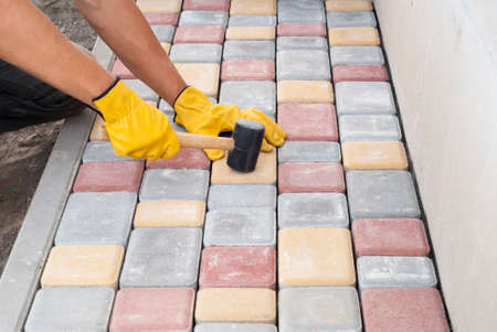 construction worker laying sidewalk tiles in the yard of the houseの写真素材