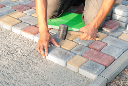 construction worker laying sidewalk tiles in the yard of the houseの写真素材