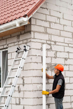 Construction worker installs pipe the gutter systemの写真素材