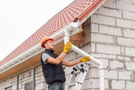 Construction worker installs the gutter system on the roofの写真素材