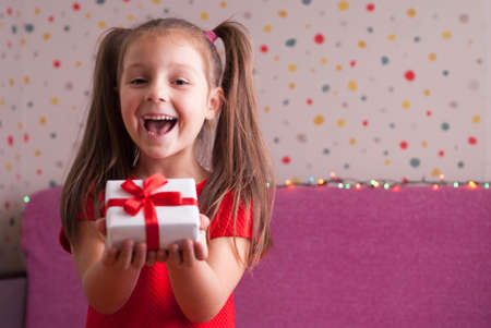 very cute little girl holding a box with a giftの写真素材