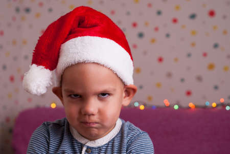 boy in a santa hat angrily looksの写真素材