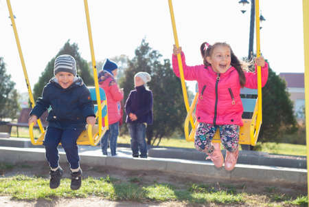 little girl and boy ride on a swingの写真素材