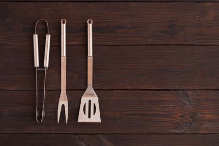 kitchen tongs, fork for meat and spatula on a wooden backgroundの写真素材
