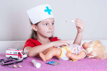 little girl doctor playing with a dollの写真素材