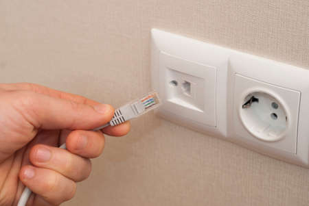 network cable connector in the hand on a background of outletsの写真素材