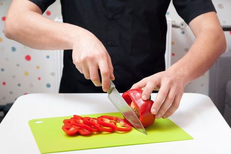 man cuts a paprika on a green cutting board
