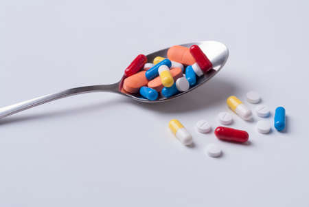 medical pills and spoon on a white backgroundの写真素材