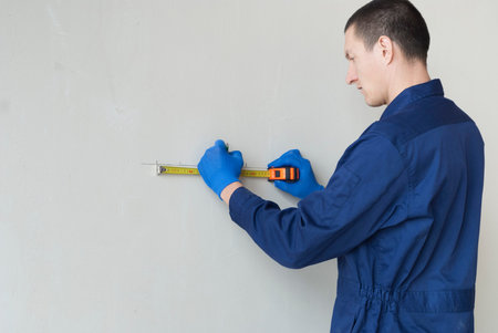 electrical worker performs marks on the wall for the installation of sockets