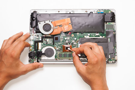repairman cleans laptop processor from old thermal paste