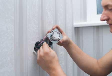 worker installs an lighting switch in the house