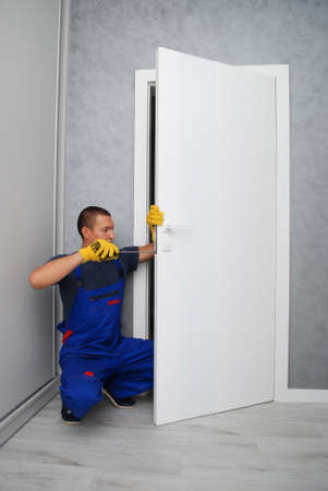 the worker with screwdriver is repairing a door lockの写真素材