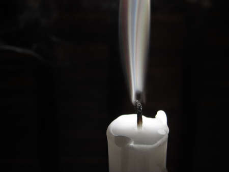 white candle off with smoke on black backgroundの写真素材