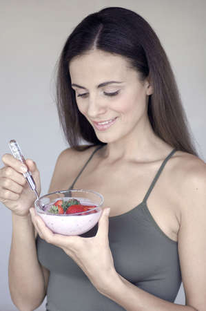 Eating yogurth and strawberriesの写真素材