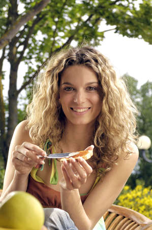 Beautiful blond woman having breakfast in the gardenの写真素材