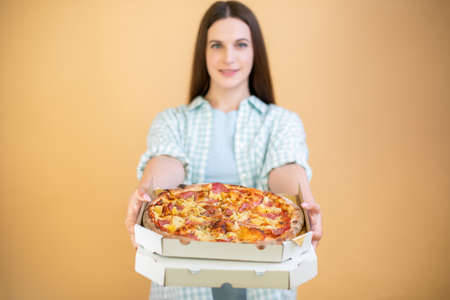 Happy young woman holding hot pizza in boxの写真素材