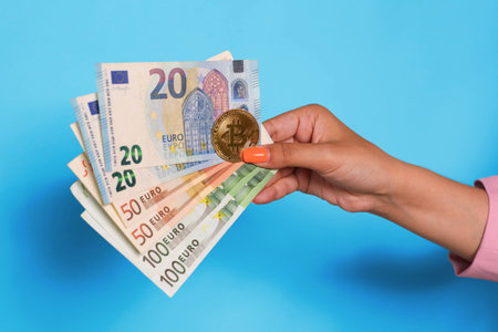 Hand holding euro currency and bitcoin over blue background