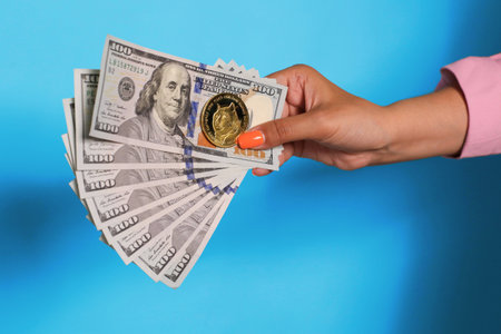 Hand holding dollar currency and dogecoin over blue background