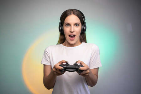 Game win. Happy female gamer in headphones rejoices in the victory in the game. Emotional gamer. Portable game consoleの写真素材