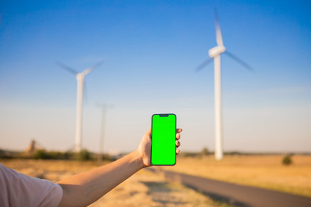 Green screen smartphone on the windmills background. Chroma key. windmills green energy