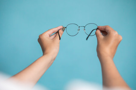 Female hand with stylish glasses on colorful backgroundの写真素材