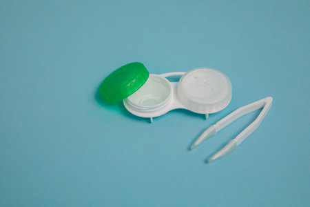 Case with contact lenses and tweezers on light blue backgroundの写真素材
