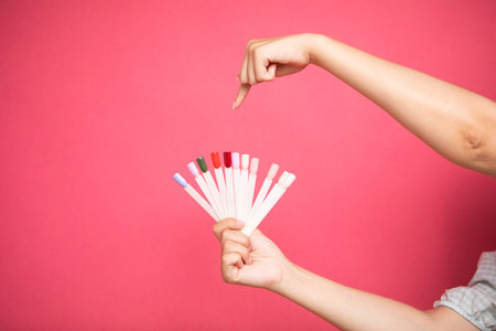 Fan of nail art polish tips samples in woman hand and points to one of themの写真素材