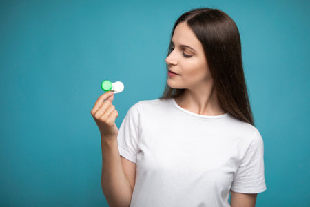Young woman holding contact lenses looking at lens containerの写真素材