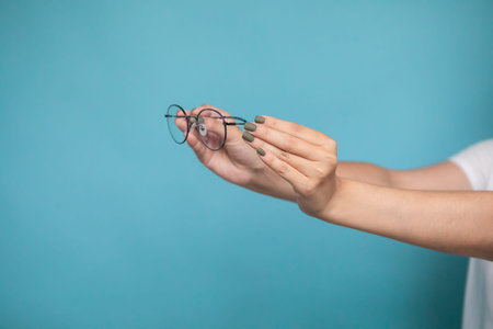 Female hand with stylish glasses on colorful background