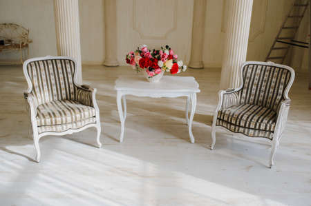 white vintage old studio room with two chairs and table with red flowersの写真素材