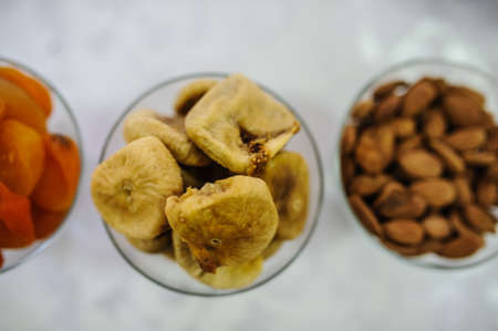 Figs, apricots, almonds in glass plate isolated on white backgroundの写真素材