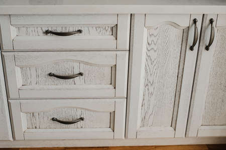 antique white painted cupboard closet, old hand made furniture in wood with drawers and doorsの写真素材