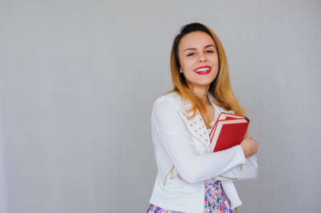 portrait of young student holding a  book over grey backgroundの写真素材