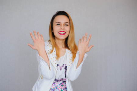 Happy attractive girl standing over gray background and looking at camera and smiling