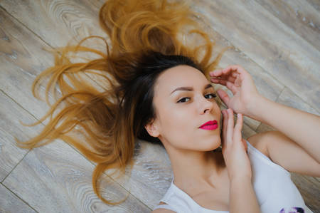 happy young woman lying on wooden parquet floor relaxed at home looking upの写真素材