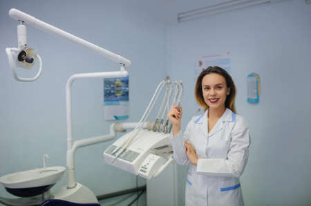 portrait of smile young woman dentist in dental treatment room with turbineの写真素材