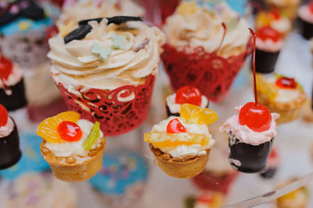 Delicious sweet cupcakes with cherry, kiwi, orange on a partyの写真素材