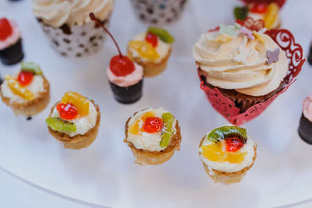 Delicious sweet cupcakes with cherry, kiwi, orange on a partyの写真素材