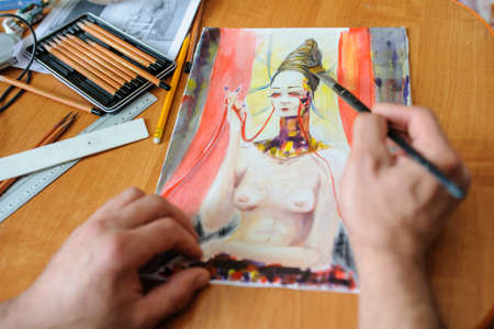 Young man painting a picture of a woman with brushの写真素材