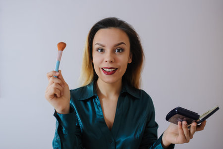 Portrait of sexy smiling happy caucasian young woman applying foundation blusher with makeup brush