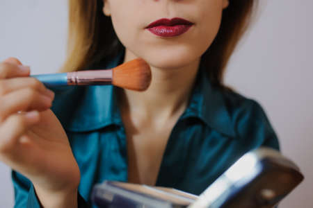 Makeup applying closeup. Cosmetic Powder Brush. Perfect Skin. Red lipsの写真素材