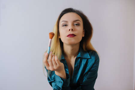 Portrait of sexy smiling happy caucasian young woman applying foundation blusher with makeup brushの写真素材