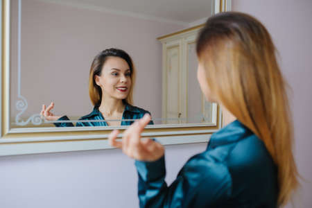 Young sexy woman looking in the mirror and smiling の写真素材