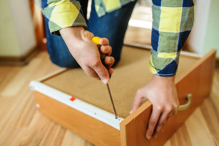 Close-up of the process of installation a furniture facade. Woman's hands working with a screwdriverの写真素材