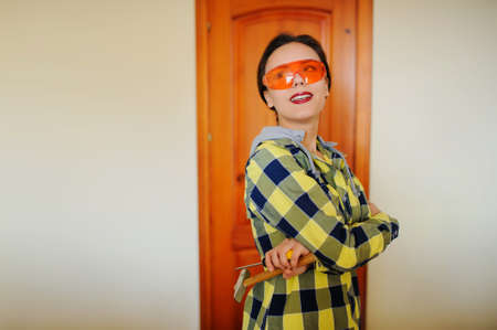 Attractive smiling builder woman with hammer and orange protective glassesの写真素材