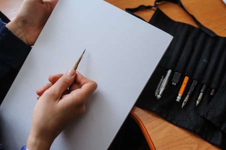 Top view of female hands with pencil on blank white paper sheet starting new pictureの写真素材